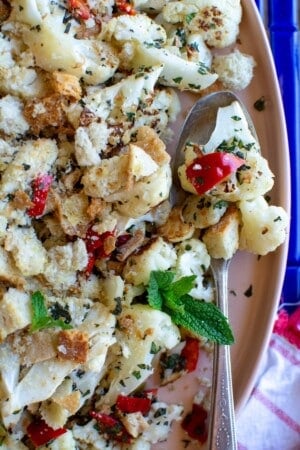 Roasted cauliflower with pickled cherry peppers on a pink platter