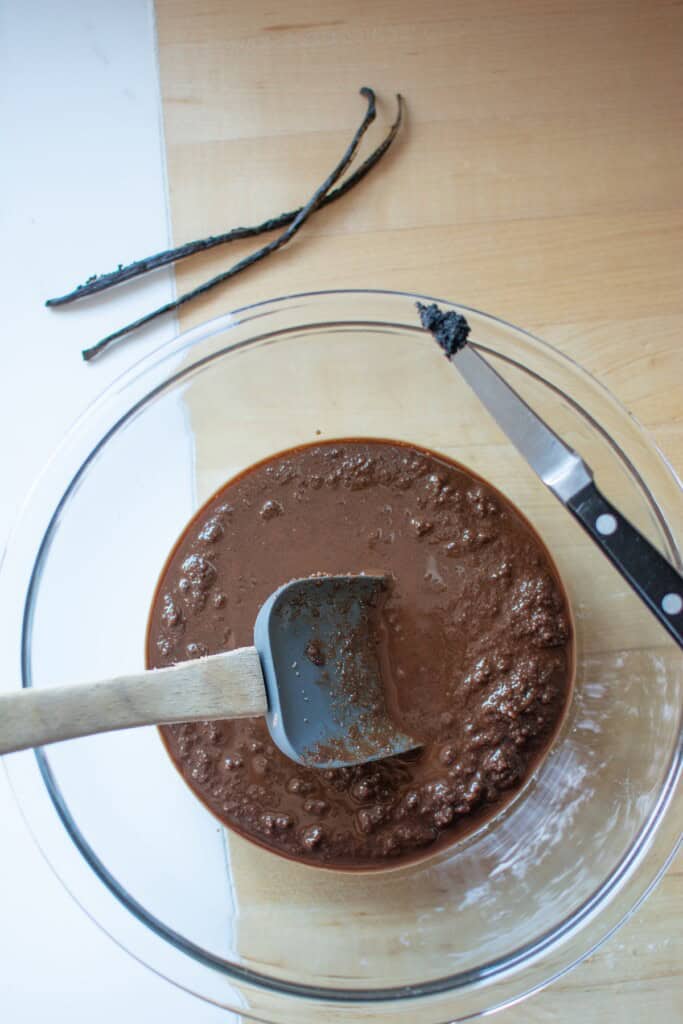 A bowl of brownie batter with vanilla bean next to it. 