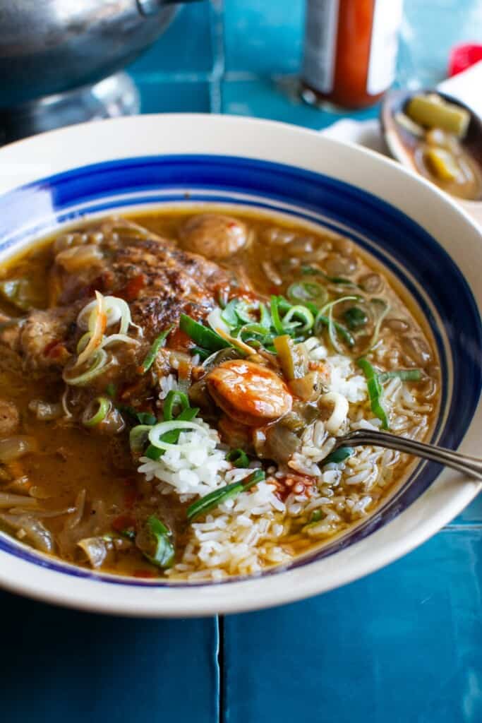 A bowl of chicken and smoked sausage gumbo with a spoon in the bowl 