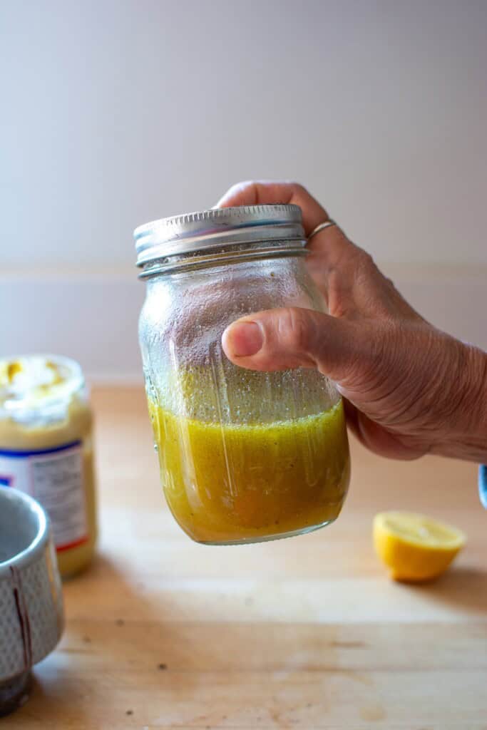 A hand holding the mason jar and shaking it up