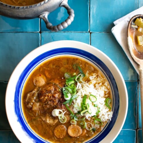 A bowl of gumbo next to a pot full of gumbo