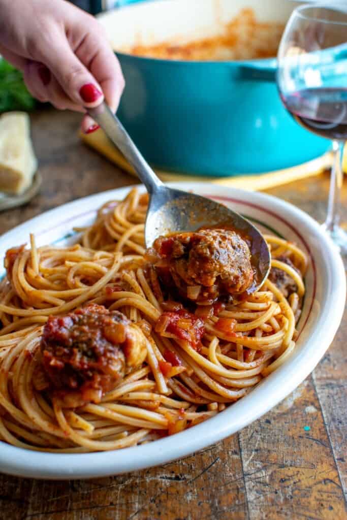 Meatballs being spooned over spaghetti 