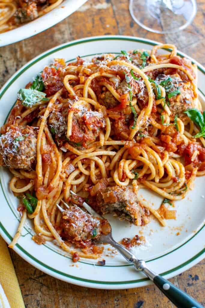 A plate of spaghetti and meatballs with a meatball cut in half. 