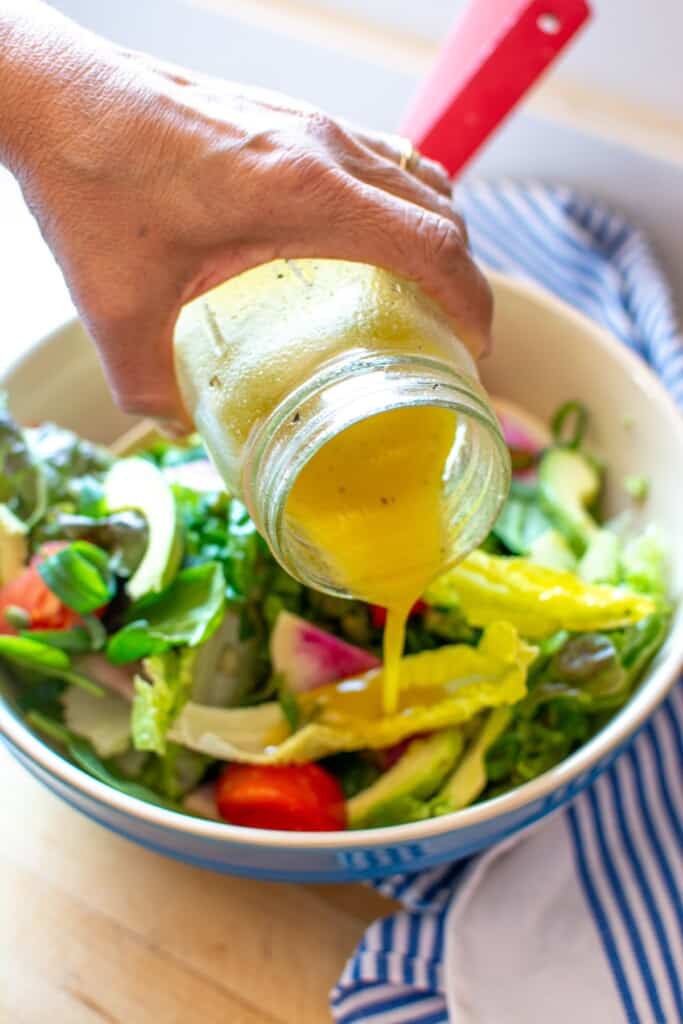 Maple mustard salad dressing being poured over a salad