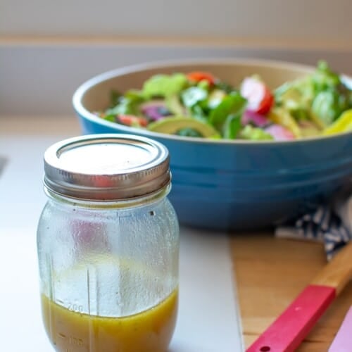 A mason jar with maple mustard salad dressing in it.