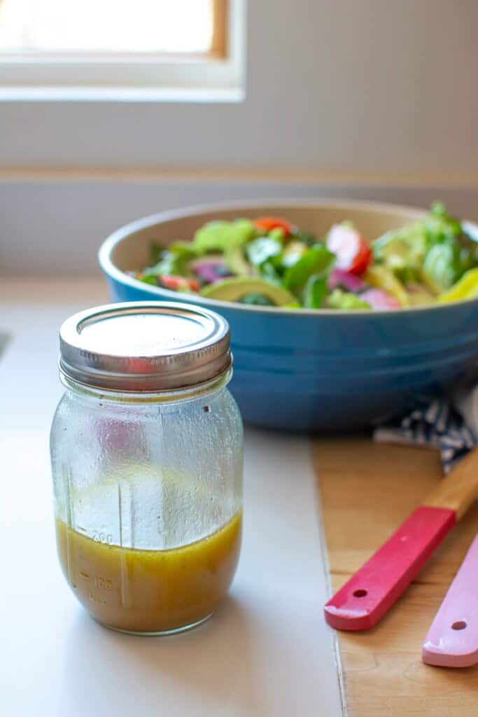 A mason jar with maple mustard salad dressing in it. 