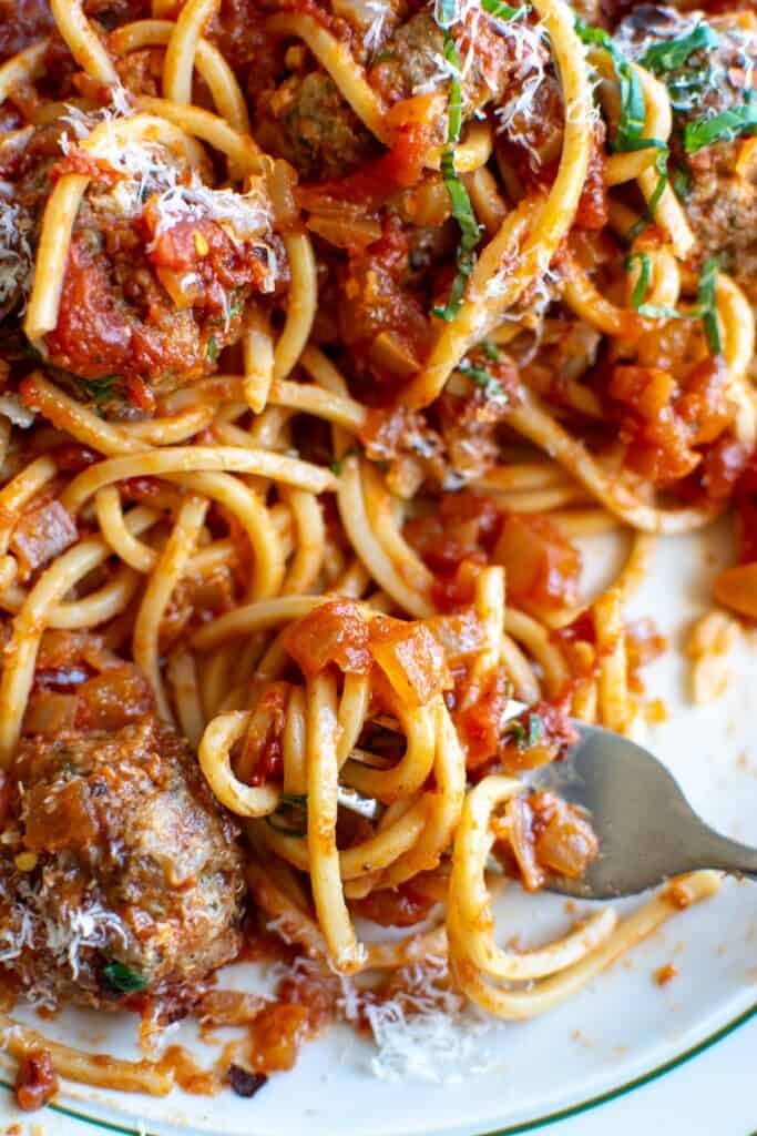 A plate of spaghetti and meatballs with a fork on the plate. 