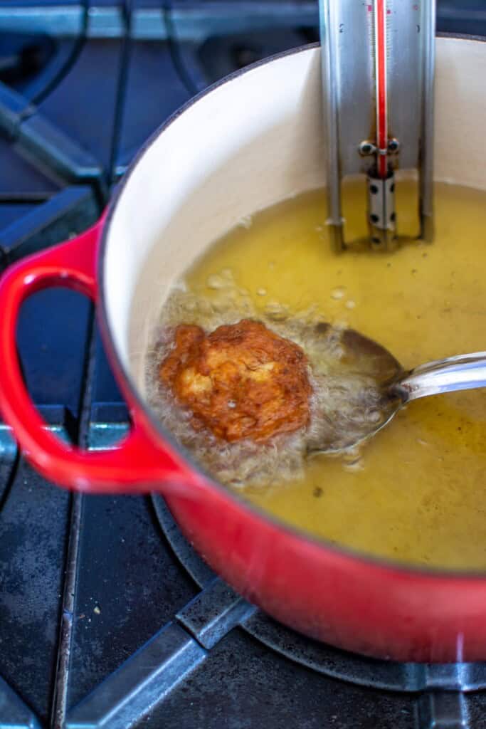 A fritter being removed with a slotted spoon