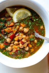 moroccan chickpea stew with lemon slices on top and a spoon in the bowl
