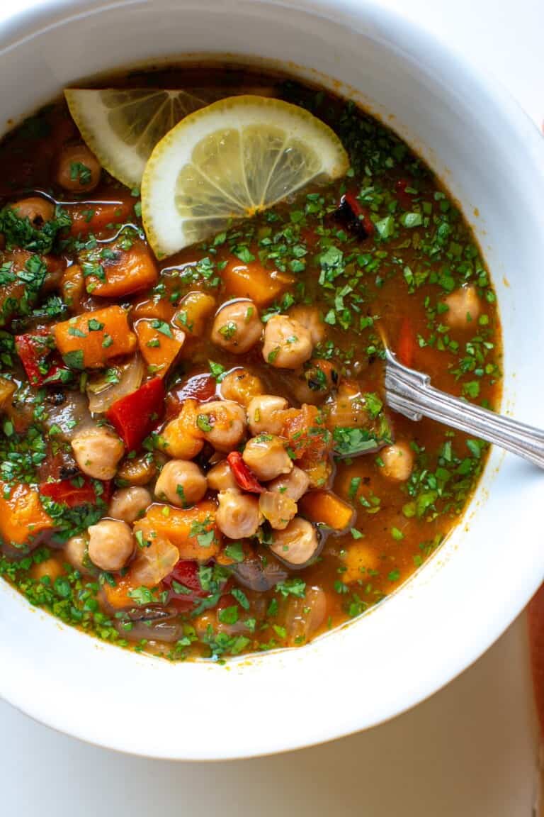 moroccan chickpea stew with lemon slices on top and a spoon in the bowl