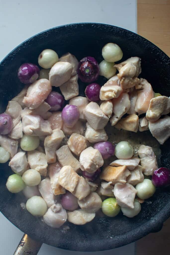 chicken and pearl onions sautéing in a pan