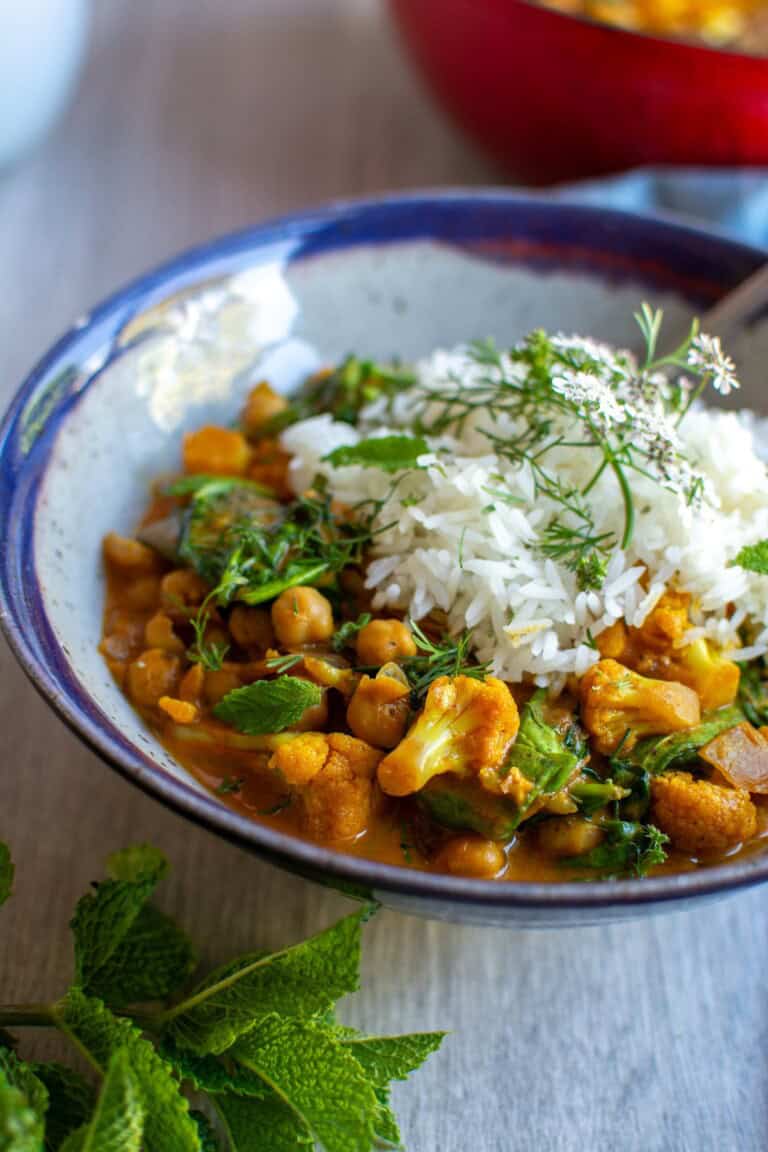 A bowl of vegetable curry with rice on top