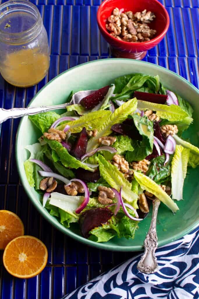 A green bowl of crunchy romaine salad on a blue back ground