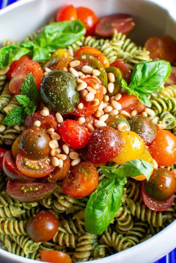 A bowl of whole wheat pasta salad with cherry tomatoes on top.