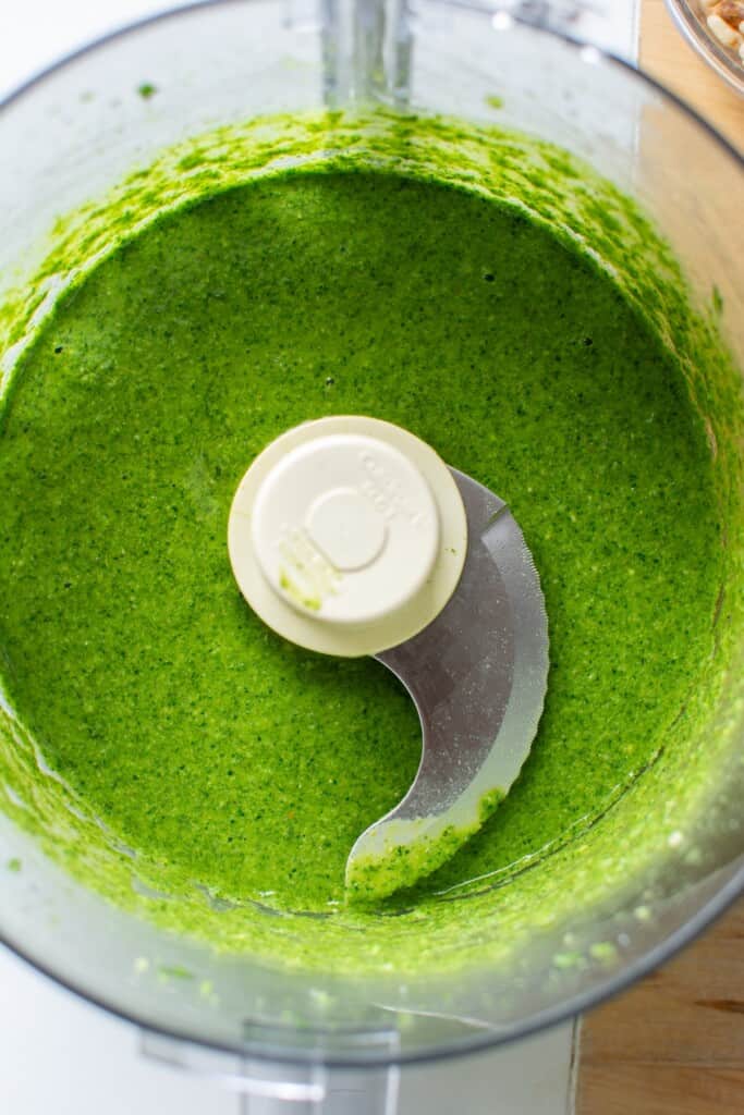 A green pesto in the bowl of a food processor