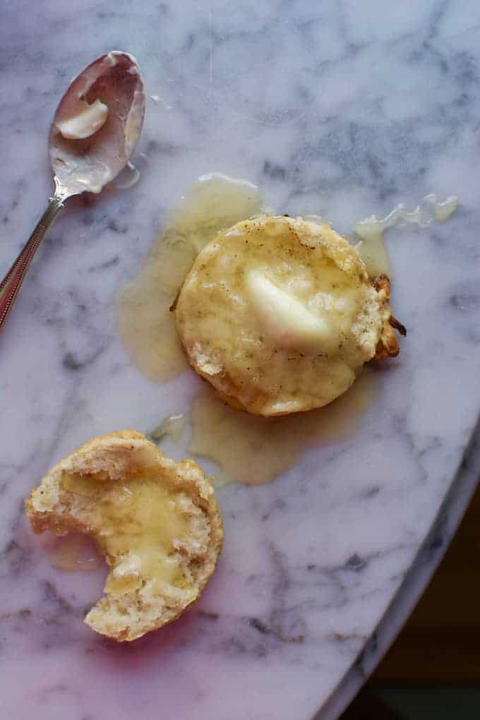 A biscuit split in half and topped with butter and honey. 