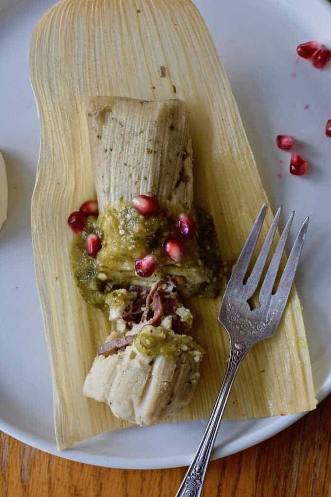 An apple-braised beef tamal cut open on a plate. 
