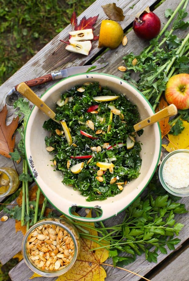 A bowl of kale salad with apples and two forks in the bowl. 