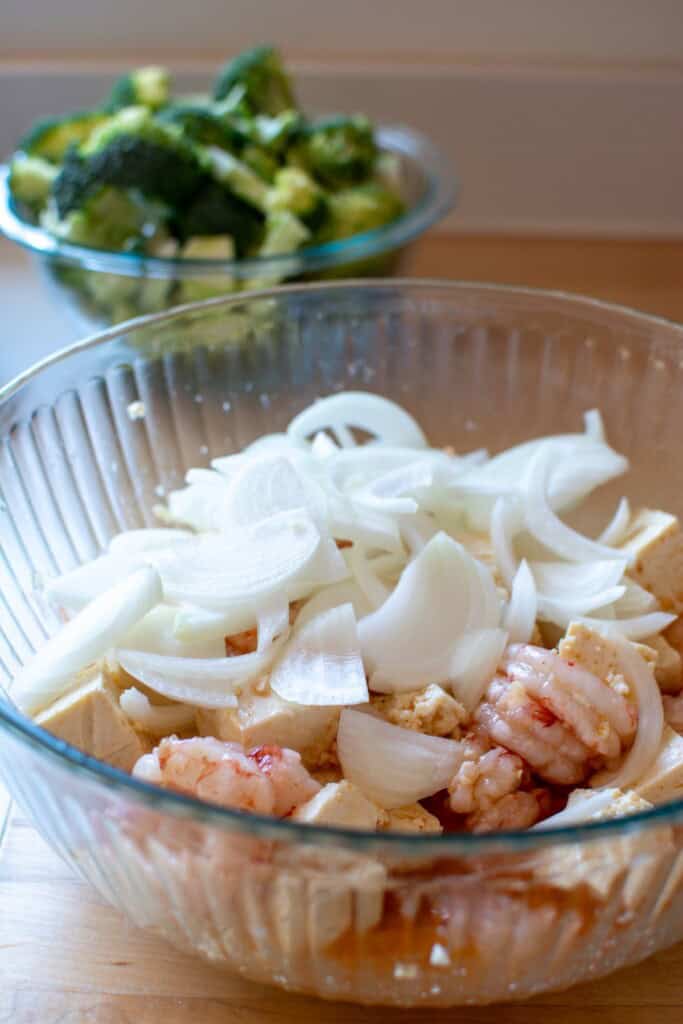 The shrimp, tofu, and onions in a large bowl with the marinade