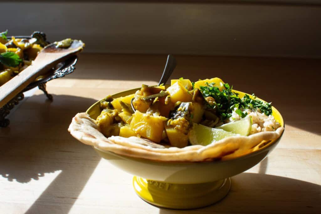 A dish of eggplant curry on a wood counter