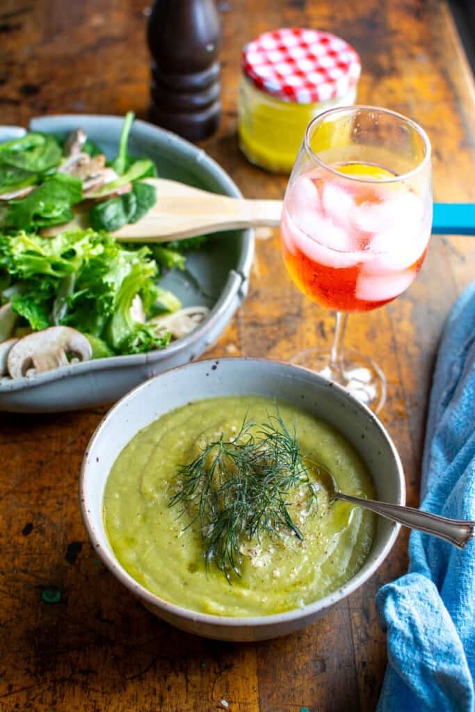 A bowl of soup next to a bowl of spinach salad