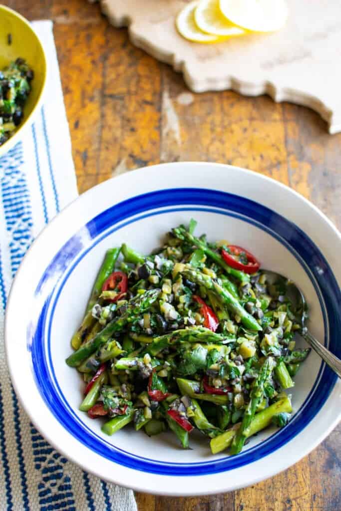 a grilled asparagus salad in a bowl with a blue rim