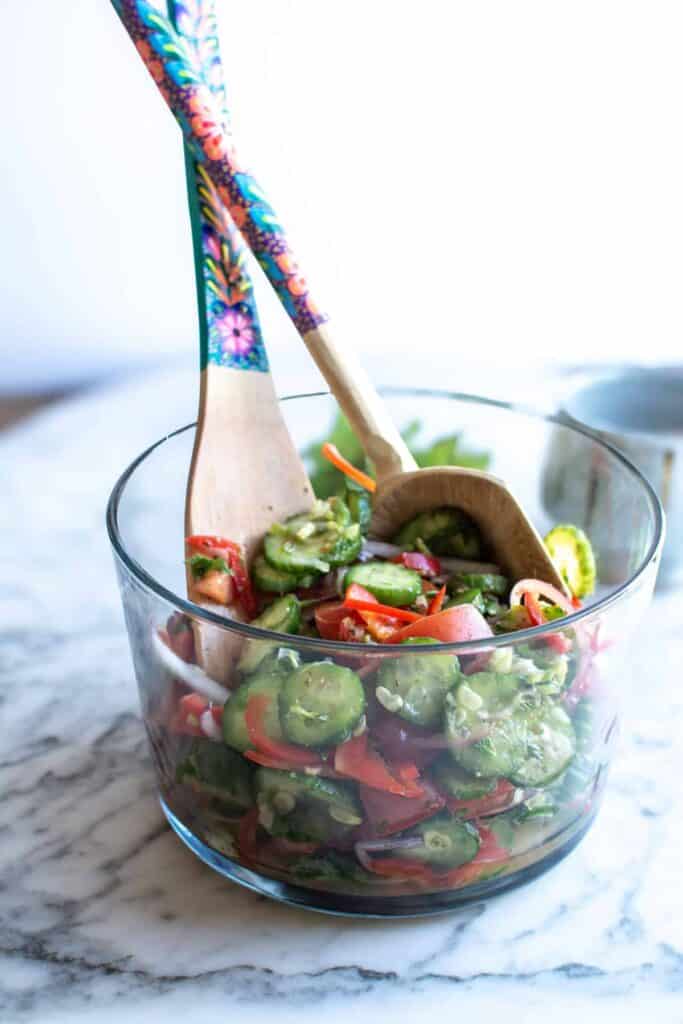 a cucumber salad in a tall glass bowl.