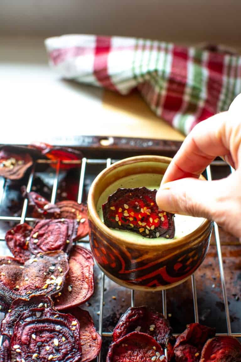 a beet chip being dipped into a green dip