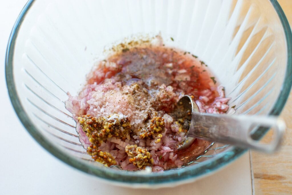 A glass bowl with salad dressing in it. 