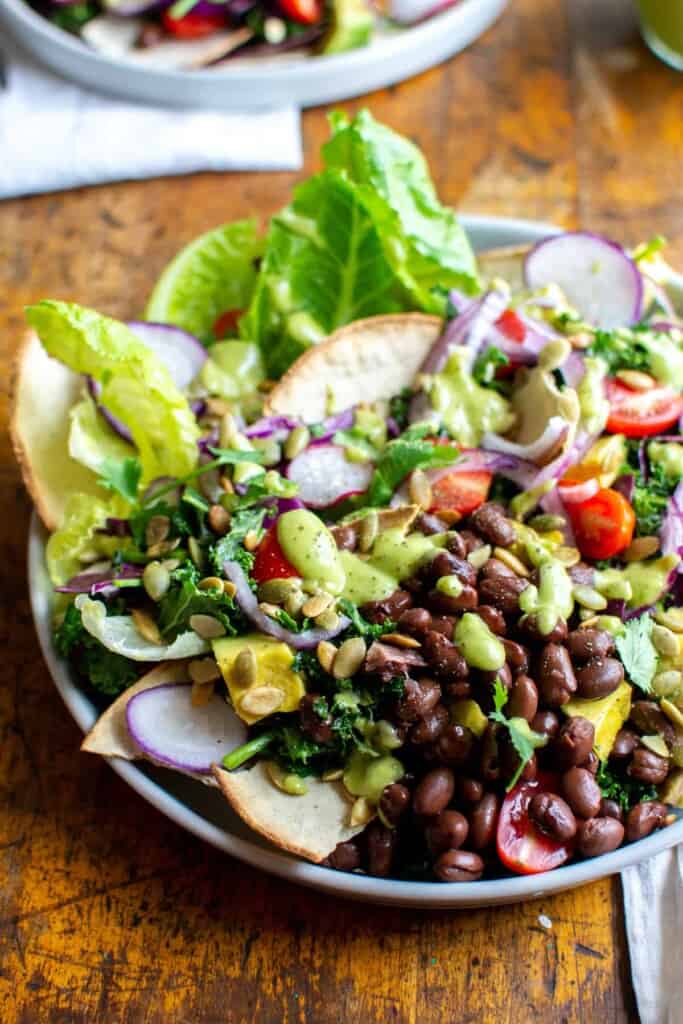 A salad with black beans and lettuce on a wood table