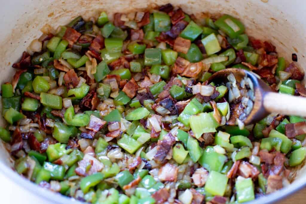 green bell peppers cooking with bacon in a pot