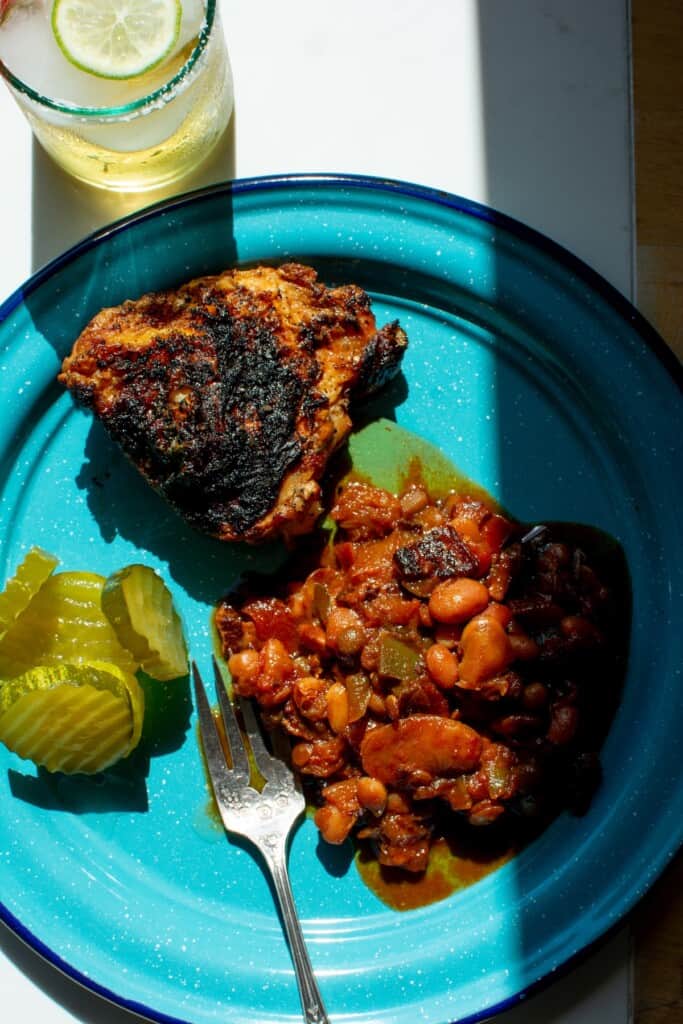 baked beans on a blue plate next to chicken