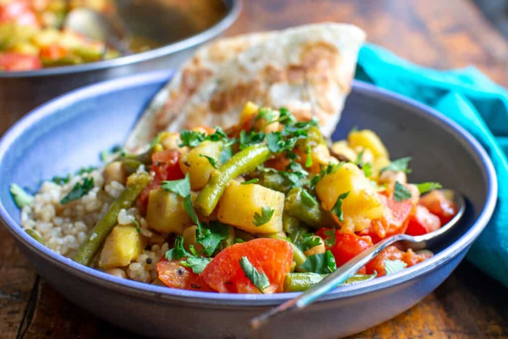potato curry with green beans in a blue bowl.