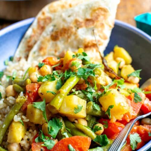 a vegan potato and green bean curry in a blue bowl