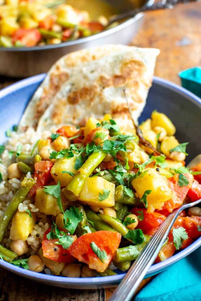 a vegan potato and green bean curry in a blue bowl