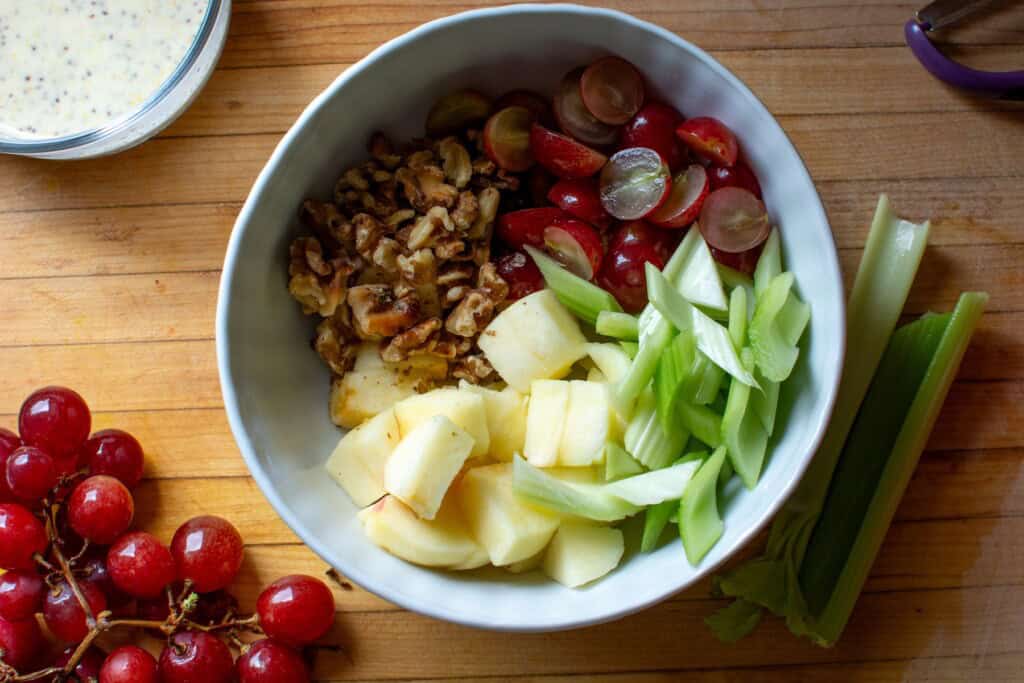 walnuts, apples, and celery in a white bowl