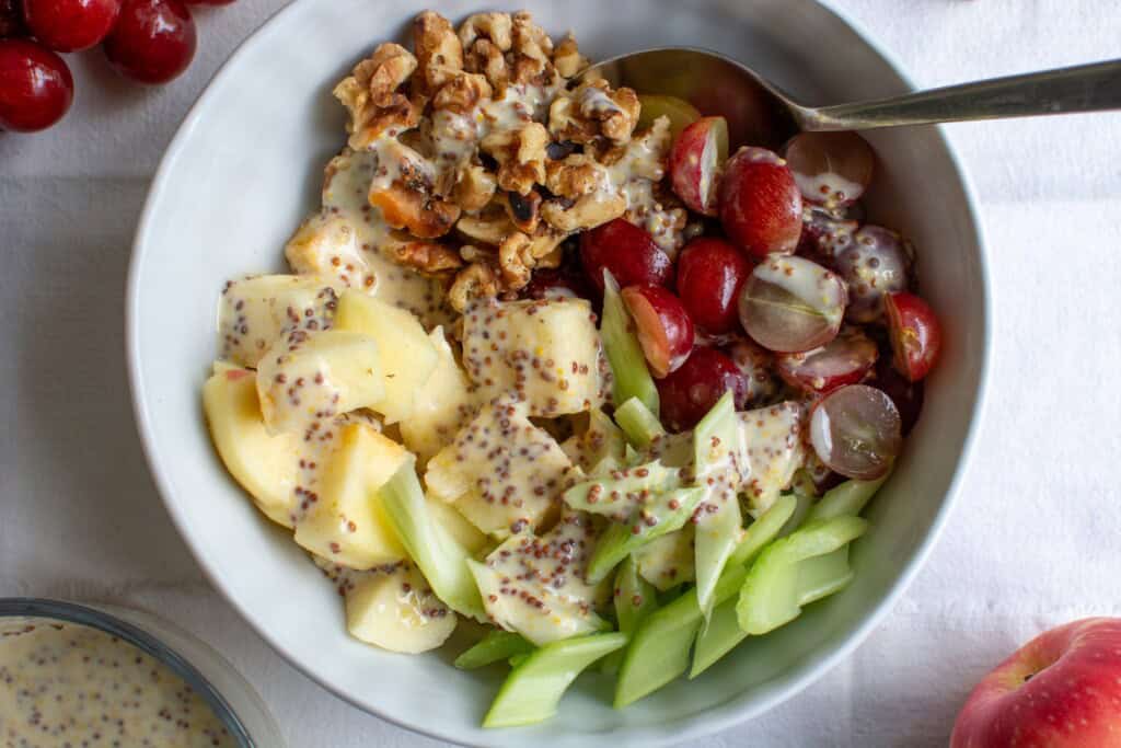 apples, walnuts, and celery in a white bowl