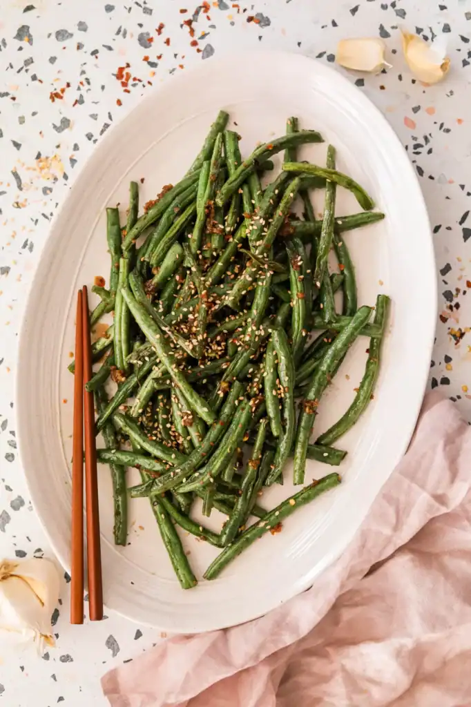roasted green beans with sesame seeds in a white dish