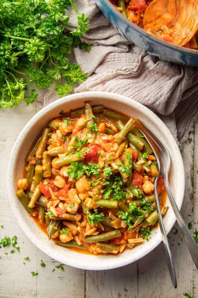 green bean stew with a spoon and fork on the side