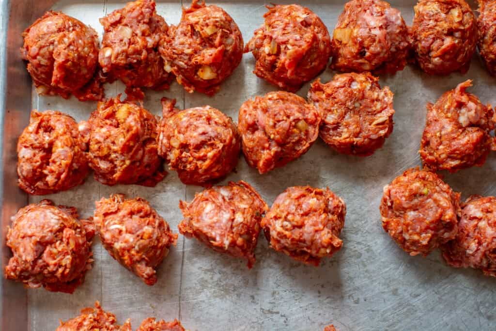 uncooked meatballs on a baking sheet