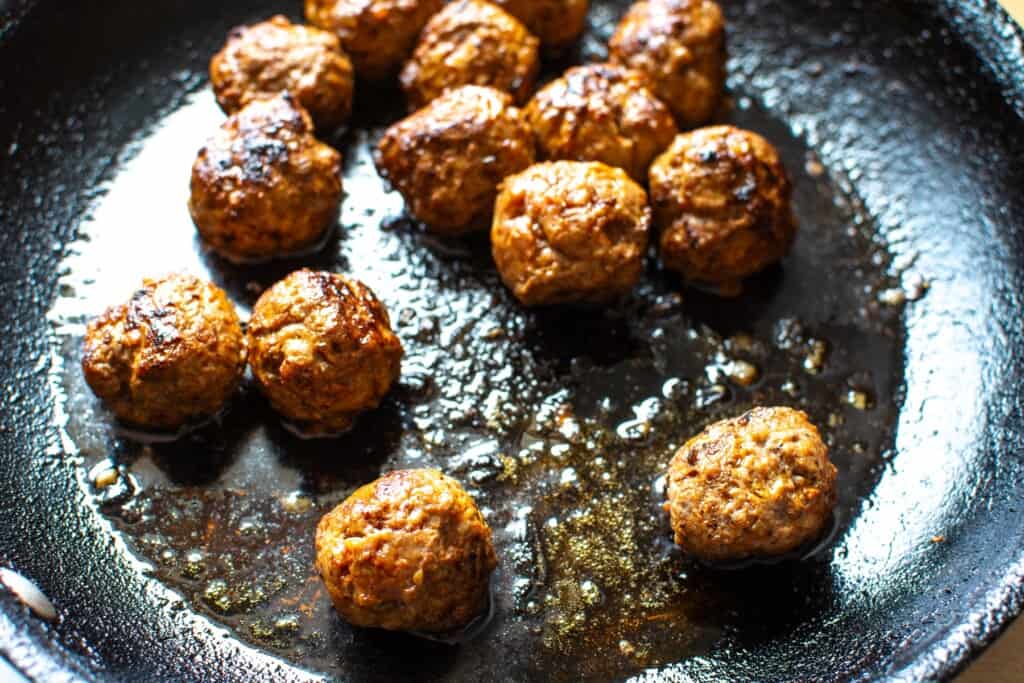 turkish meatballs cooking in a black pan