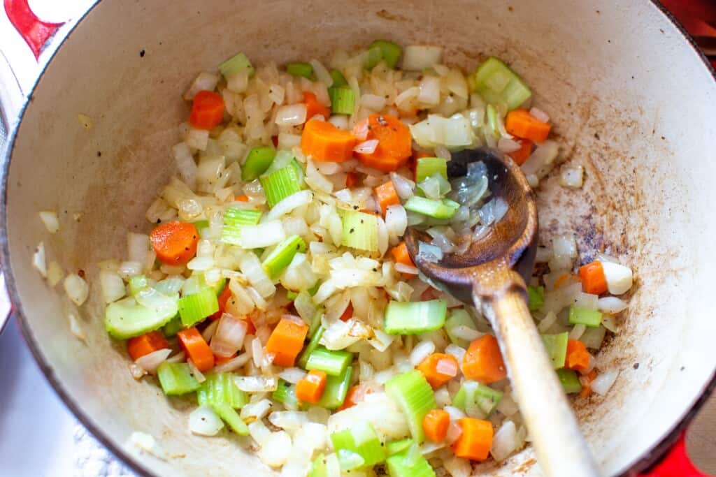 vegetables in a soup pot with a wooden spoon