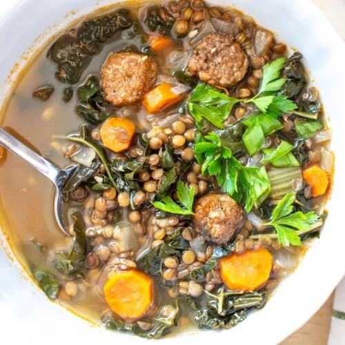 Italian lentil soup with sausage in a white bowl