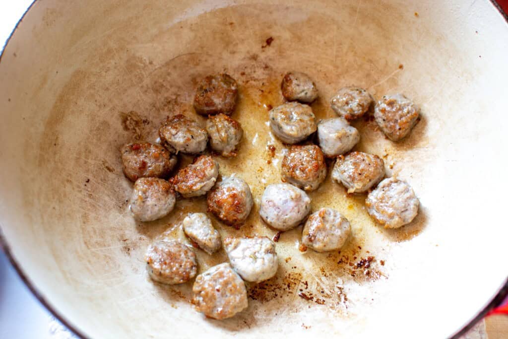 Italian sausage pieces being browned in a soup pot