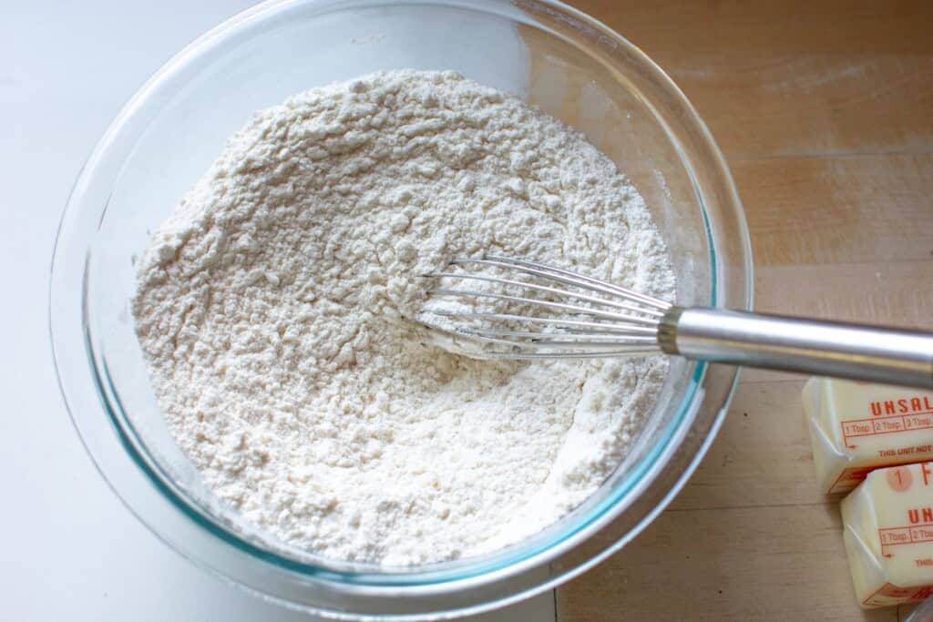The dry ingredients in a glass bowl with a whisk in the bowl