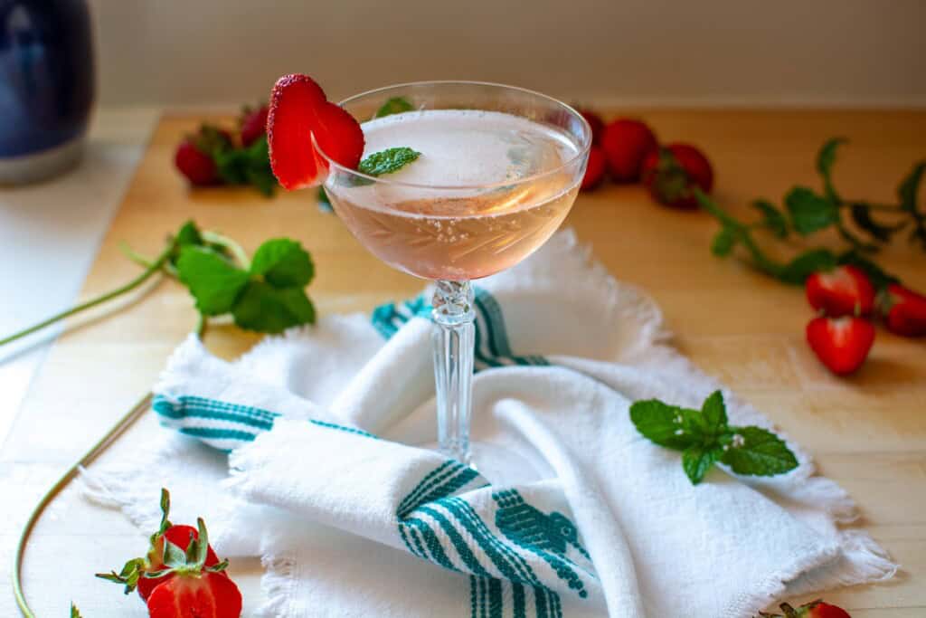 A strawberry prosecco cocktail garnished with a mint leaf