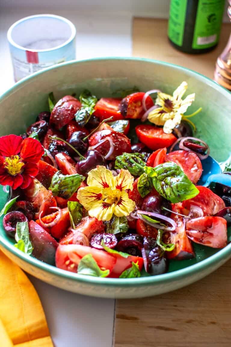 A green bowl with cherry tomatoes and tomatoes