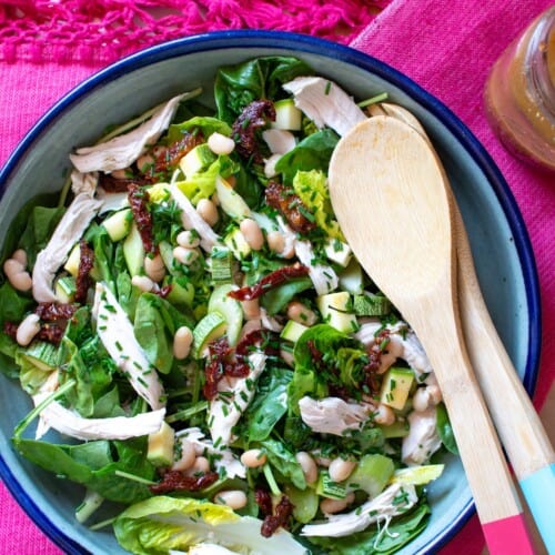 a bowl with chicken salad and wood spoons in it