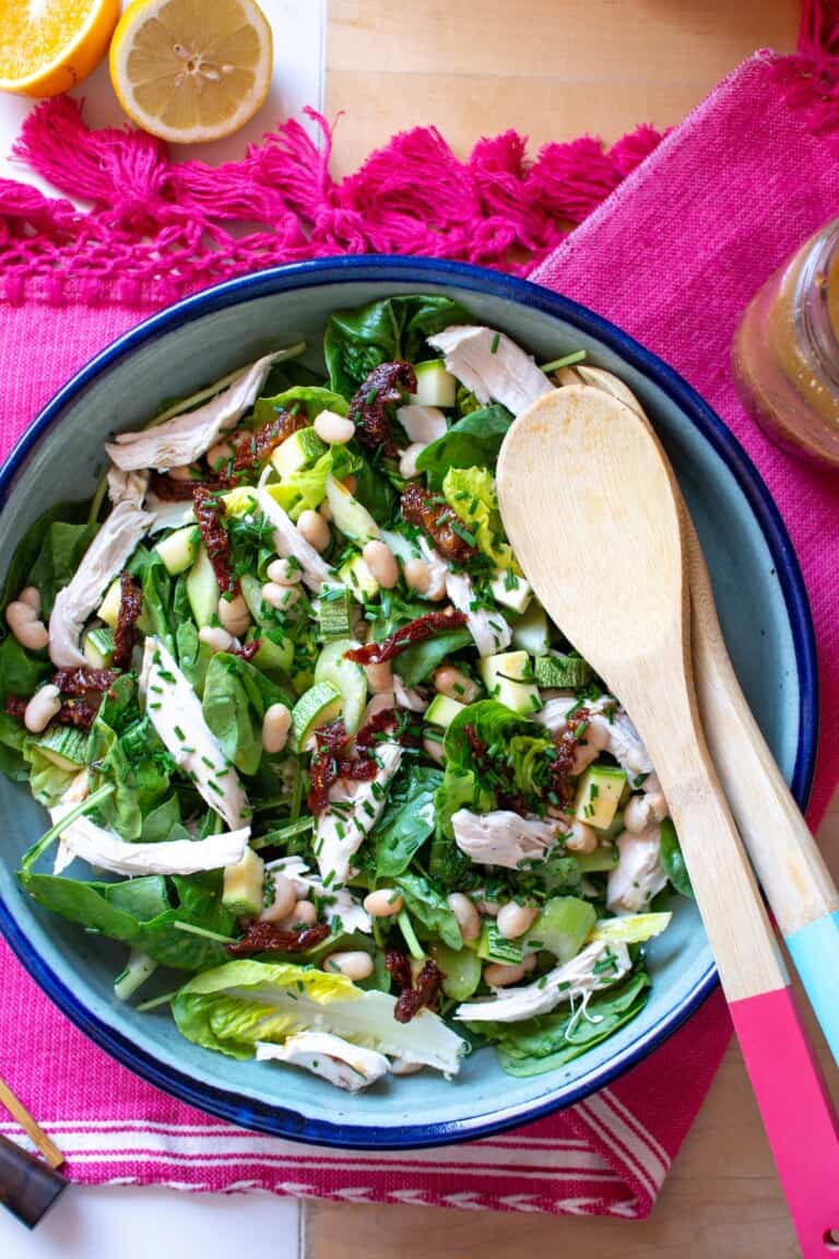 a bowl with chicken salad and wood spoons in it