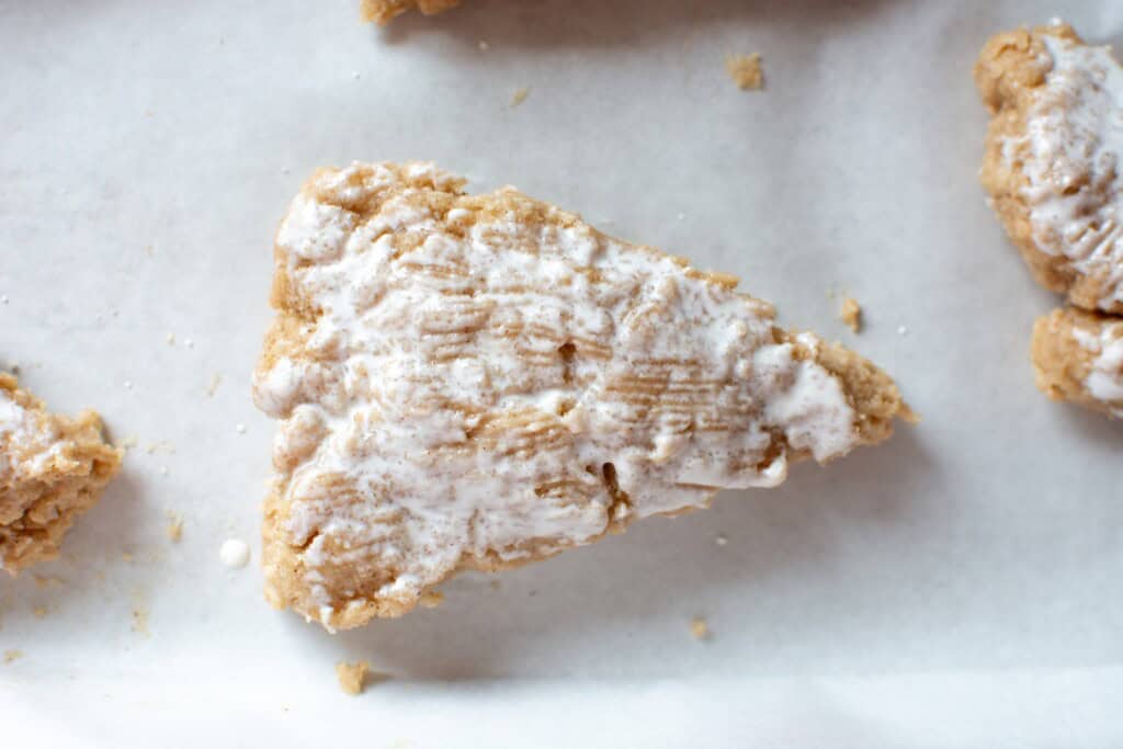 a scone brushed with cream on a baking sheet